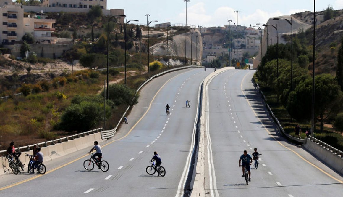 Children ride their bicycles in an empty street in Jerusalem during the Jewish holiday of Yom Kippur
